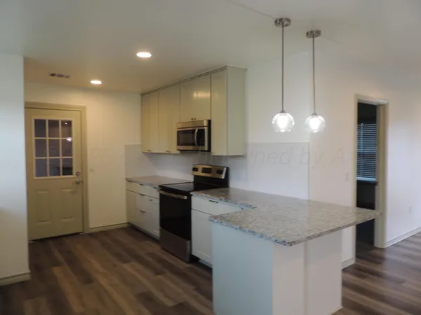 a kitchen with a sink stainless steel appliances and wooden floor
