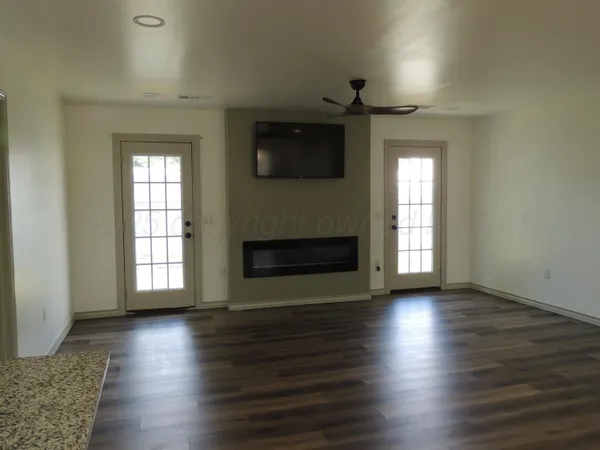 an empty room with wooden floor fireplace and windows