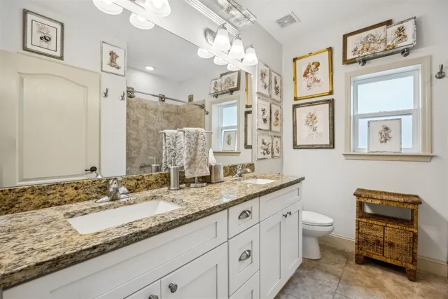 a bathroom with a granite countertop double vanity sink a mirror and a shower