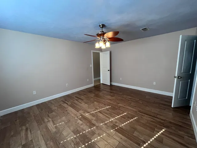a view of a room with wooden floor and a ceiling fan