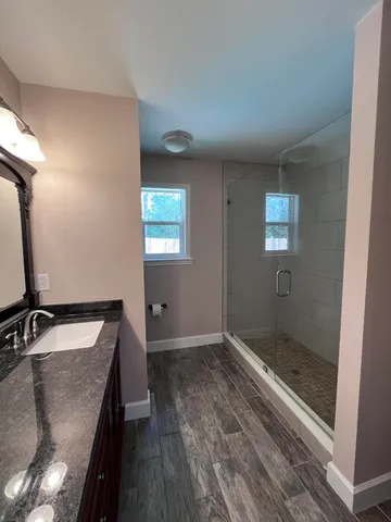 a bathroom with a granite countertop sink a mirror and a bathtub