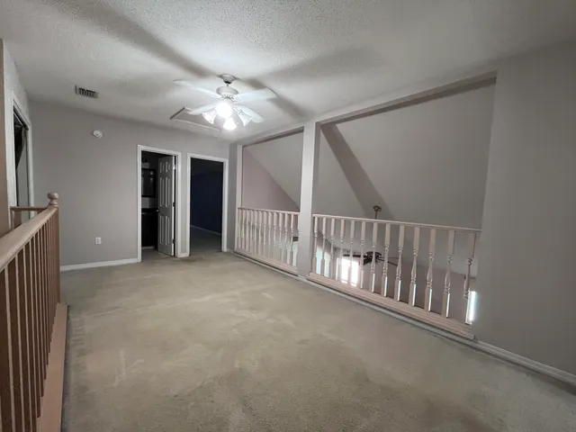 a view of an empty room with chandelier fan