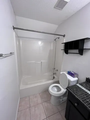 a bathroom with a granite countertop bathtub shower sink and toilet