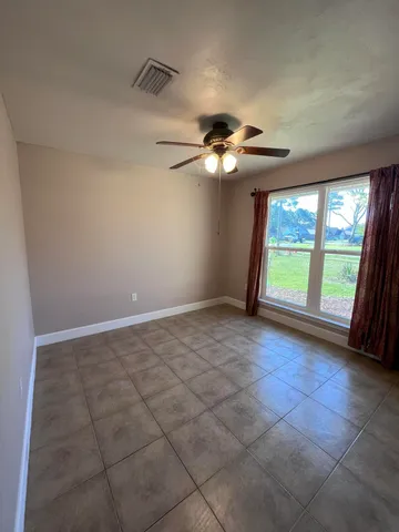 an empty room with windows and chandelier fan