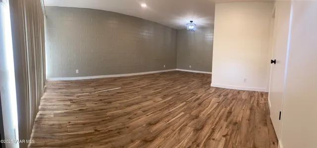 a view of empty room with wooden floor and kitchen view