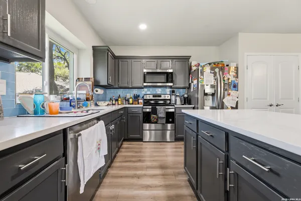a kitchen with kitchen island granite countertop a sink counter top space a stove and a window