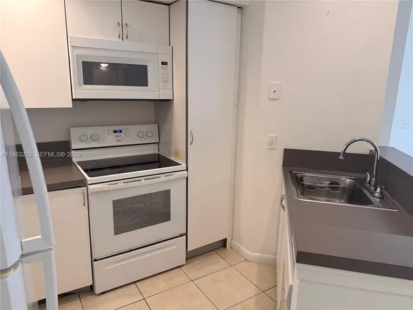 a kitchen with white cabinets and appliances