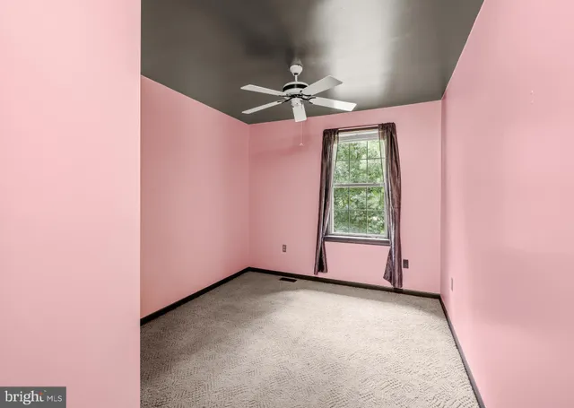 an empty room with a window and a fan