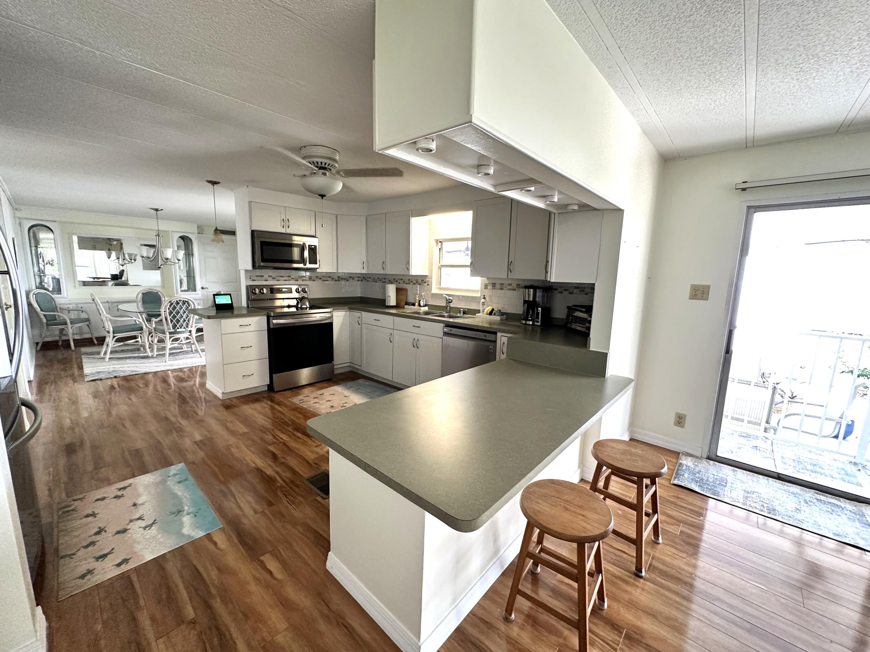 702 North Silver Circle Key Largo, FL 33037 - Photo 7 of 26 a kitchen with stainless steel appliances granite countertop a stove refrigerator dining table and chairs with wooden floor
