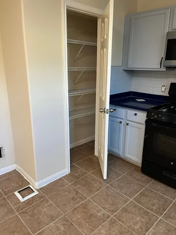 an empty room with chandelier fan and windows