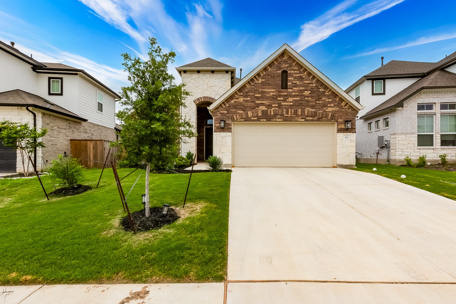 View of front facade with a garage, driveway, stone siding, and a front lawn