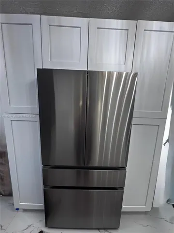 a kitchen with white cabinets and appliances