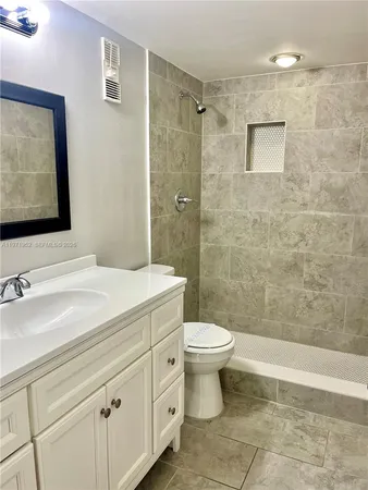 a view of an empty room with wooden floor and a bathroom