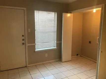 a view of an empty room with window and cabinet area