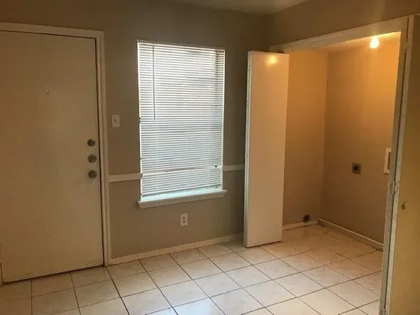 a view of an empty room with window and cabinet area