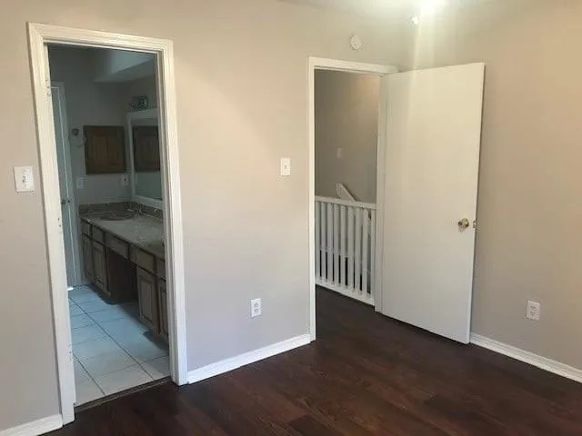 an empty room with wooden floor cabinets and a bathroom