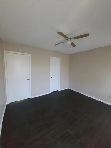a view of an empty room with a ceiling fan and wooden floor
