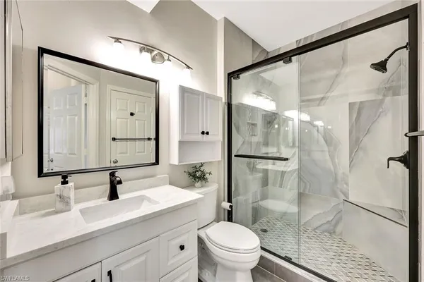 a bathroom with a sink vanity granite toilet and shower