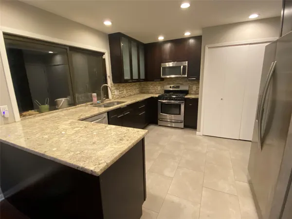 a kitchen with stainless steel appliances granite countertop a sink and a refrigerator