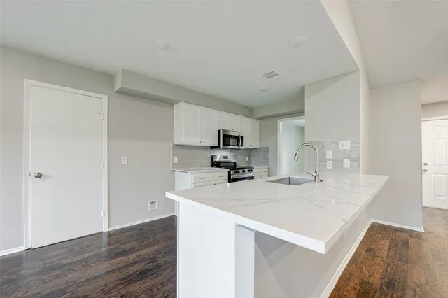 a kitchen with stainless steel appliances a sink a stove a refrigerator cabinets and a dining table