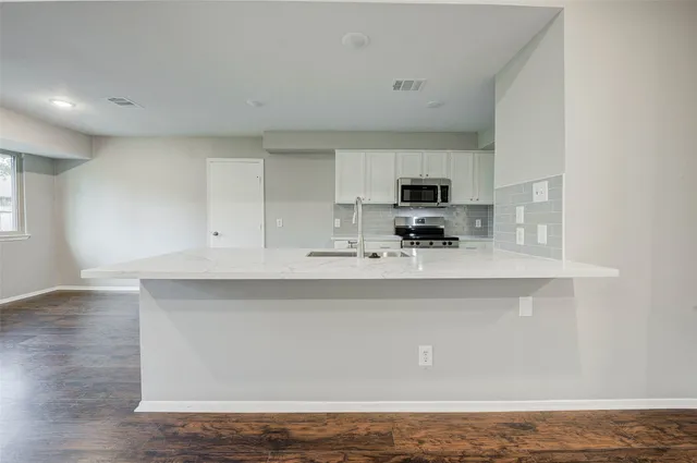 a kitchen with stainless steel appliances granite countertop a sink a stove top oven and white cabinets