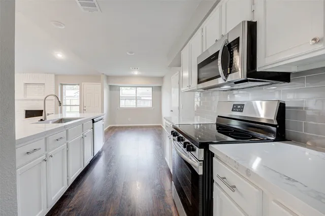 a kitchen with stainless steel appliances a stove sink microwave and cabinets