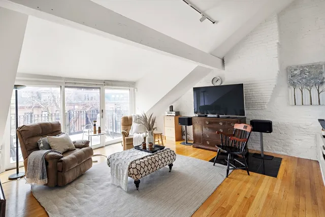 a living room with furniture floor to ceiling window hardwood floor and a flat screen tv