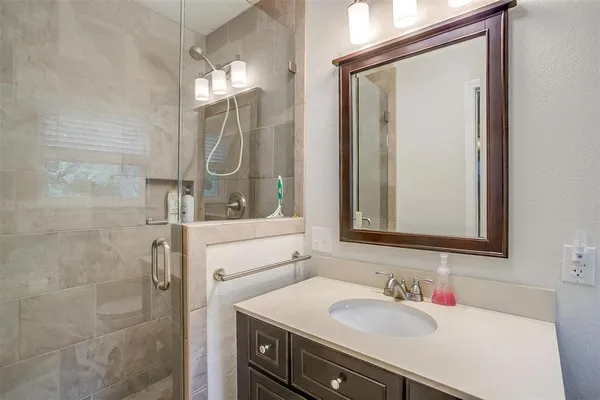 a bathroom with a sink vanity granite tub and shower