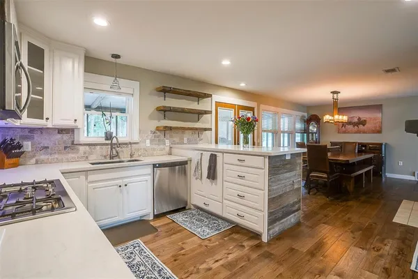 a kitchen with stainless steel appliances kitchen island granite countertop a stove a sink and a refrigerator