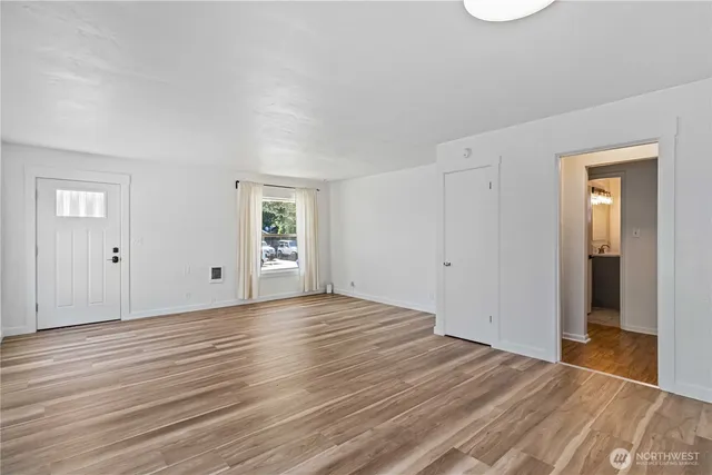 a view of an empty room with wooden floor and closet