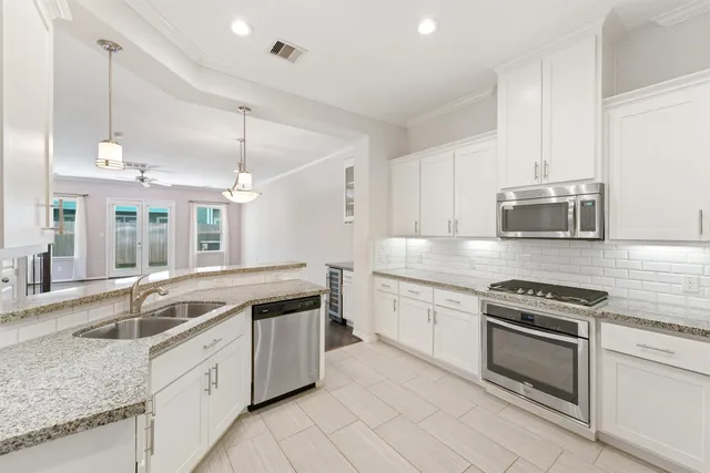 a kitchen with granite countertop a sink stainless steel appliances and cabinets