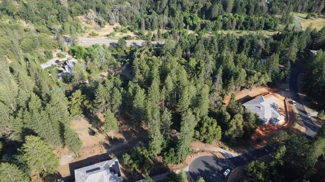 an aerial view of residential house with outdoor space and trees all around