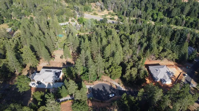 an aerial view of house with outdoor space and trees all around