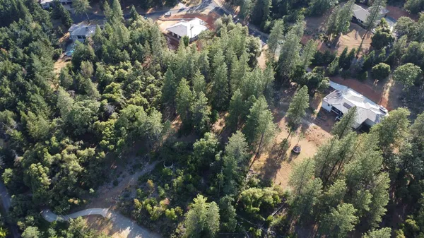 an aerial view of residential house with outdoor space and trees all around
