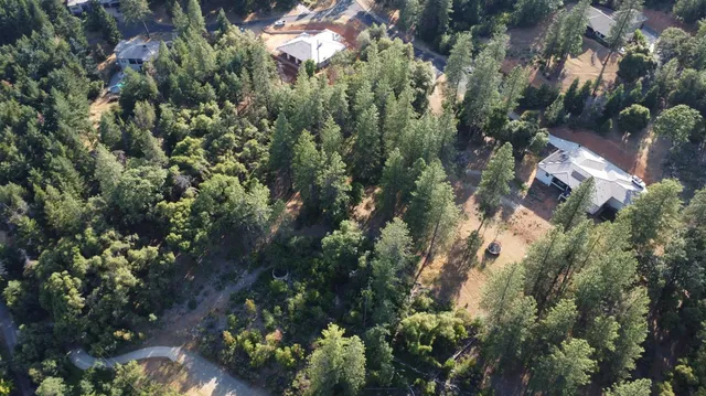 an aerial view of residential house with outdoor space and trees all around