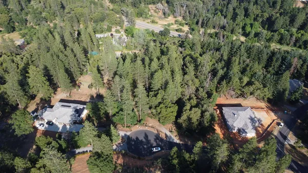 an aerial view of residential house with outdoor space and trees all around