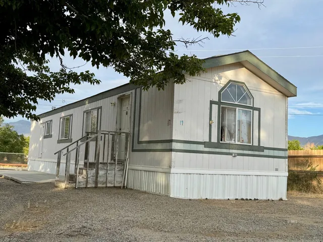 a view of a house with a large tree and wooden fence