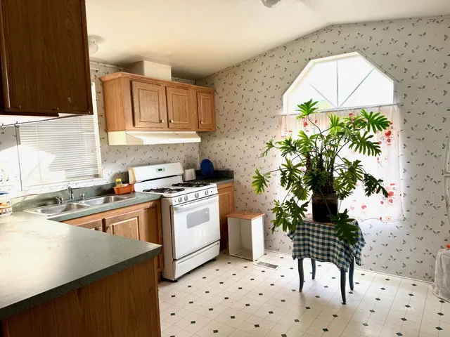 a kitchen with granite countertop a sink a stove a chimney a dining table and chairs