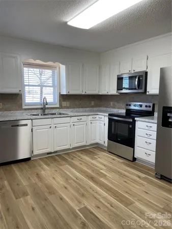 a large kitchen with stainless steel appliances granite countertop a stove a sink and a microwave