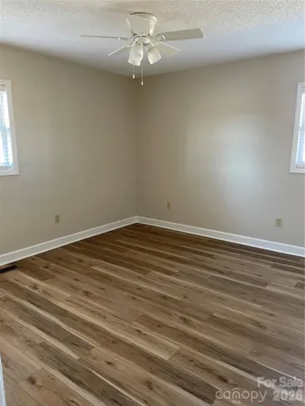 an empty room with wooden floor fan and window