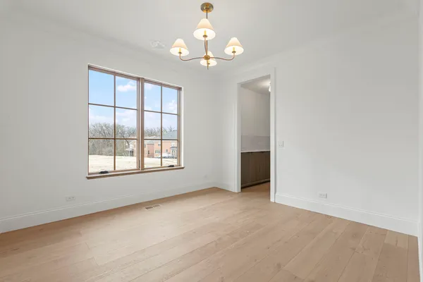 an empty room with chandelier fan and windows