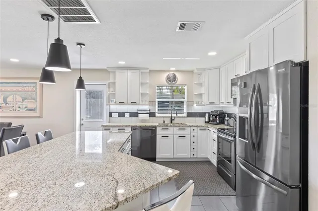 a kitchen with stainless steel appliances granite countertop a sink refrigerator and cabinets