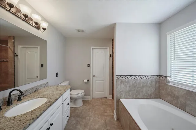 a bathroom with a granite countertop sink a toilet and bathtub
