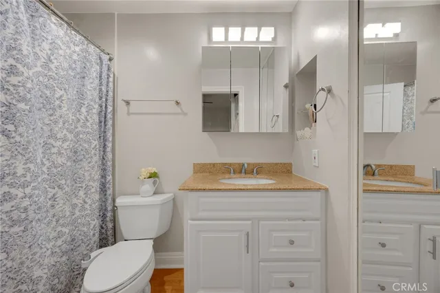 a bathroom with a granite countertop sink mirror vanity and toilet