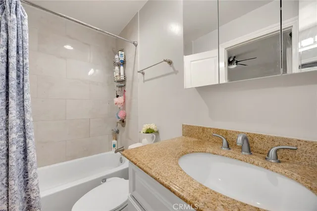 a bathroom with a granite countertop sink a toilet and bathtub