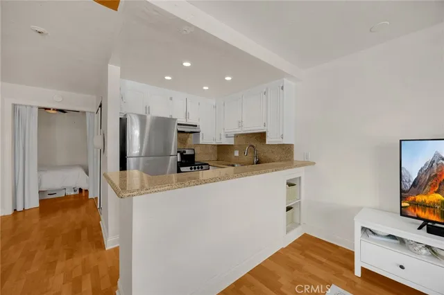 a kitchen with stainless steel appliances a refrigerator a sink a stove and white cabinets