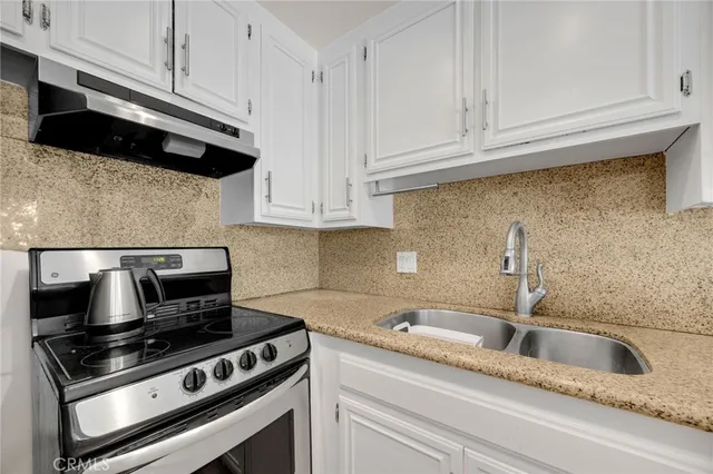 a kitchen with granite countertop a stove sink and cabinets