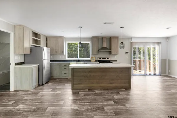 a kitchen with kitchen island granite countertop a stove top oven a sink a counter space and cabinets