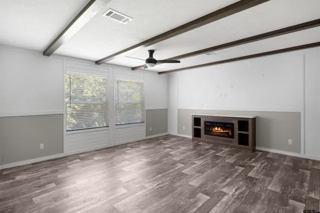 an empty room with windows fireplace and ceiling fan