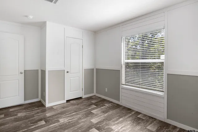 a view of empty room with wooden floor and fan
